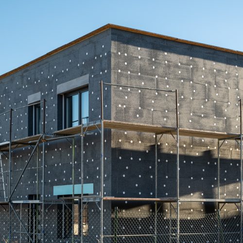 New House building in process insulation of the wall of the house with layers of modern thermal insulation materials . Exterior covering in construction site.